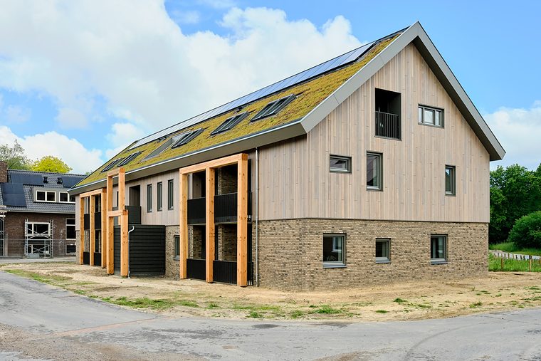 Appartementengebouw met een groot schuin sedumdak en dakkapellen