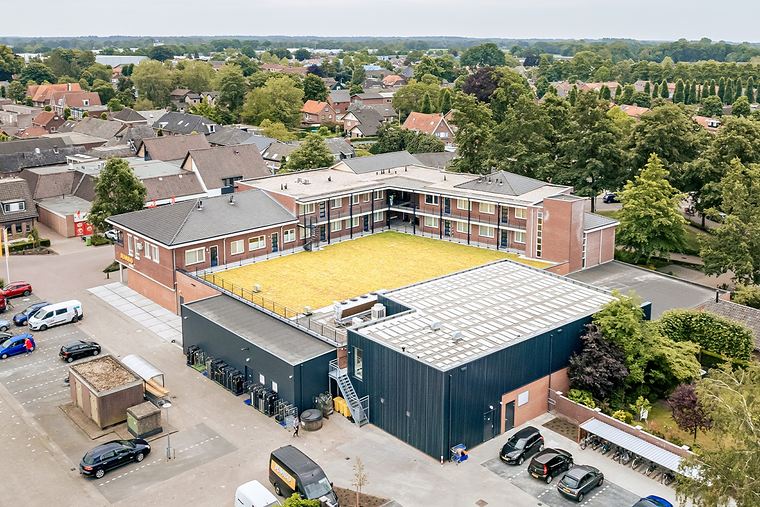 Gebouw met een geel bloeiend sedumdak rond een binnenplaats, van bovenaf gezien