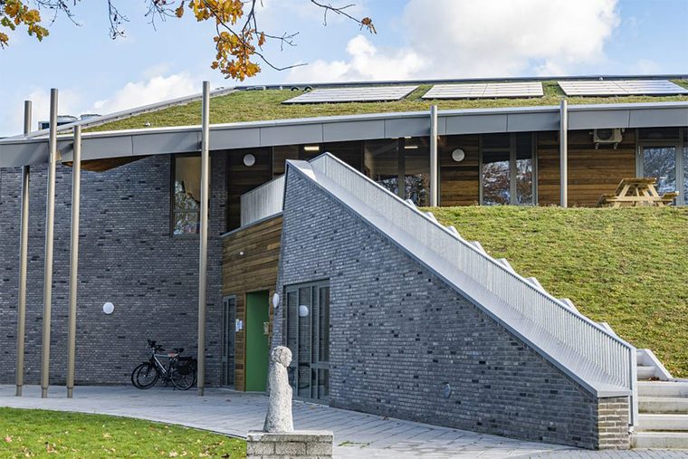 Kindcentrum met een schuin groen dak dat doorloopt tot bijna op de grond