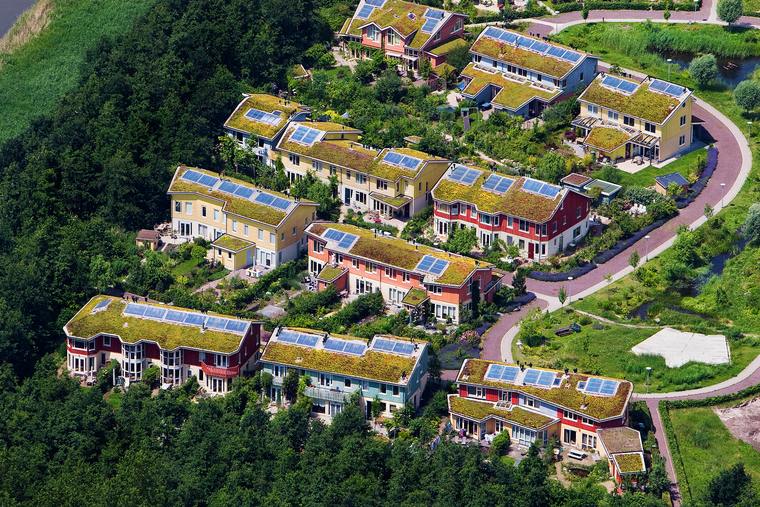 Woonwijk met groene daken en zonnepanelen tussen het groen