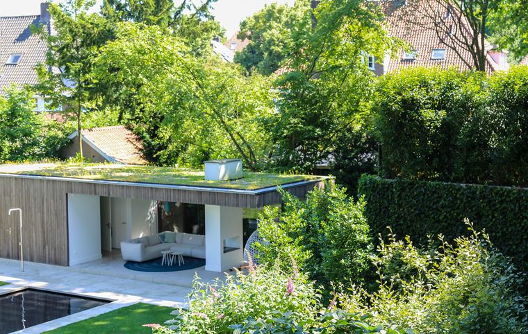 Groen sedumdak op een houten poolhouse met een overdekte zithoek