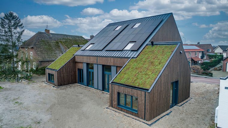 Houten woning met sedum op de lage schuine daken en zonnepanelen op het hoge dak