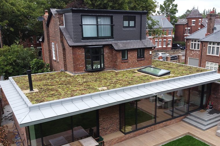 Uitbouw met een plat sedumdak en een strakke dakrand aan de tuinkant